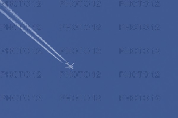 Airbus jet passenger aircraft flying in a blue sky with contrails or vapour trails behind, England,