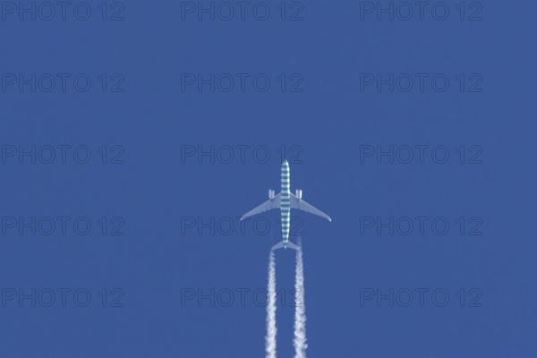 Boeing jet passenger aircraft flying in a blue sky with contrails or vapour trails behind, England,