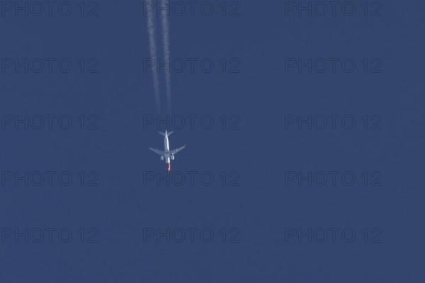 Boeing 737 jet passenger aircraft of Norwegian Air airlines flying in a blue sky with contrails or