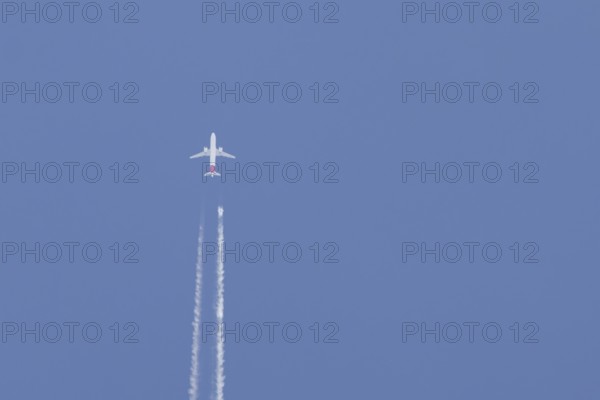 Airbus jet passenger aircraft flying in a blue sky with contrails or vapour trails behind, England,