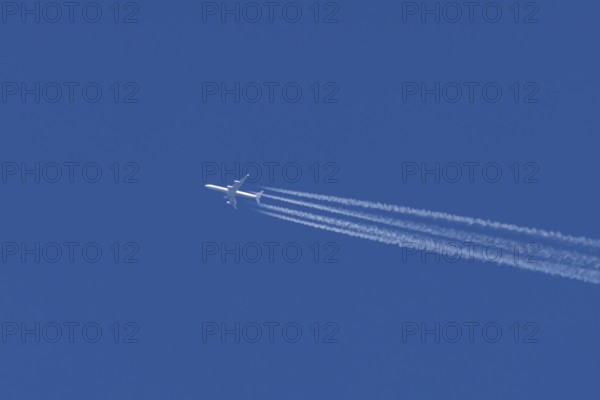 Airbus A340 jet passenger aircraft of Lufthansa airlines flying in a blue sky with contrails or