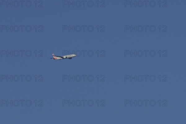 Boeing 777 jet passenger aircraft of American airlines flying in a blue sky, England, United