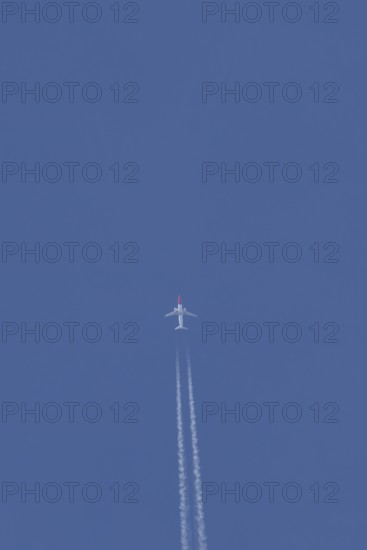 Boeing 737 jet passenger aircraft of Norwegian Air airlines flying in a blue sky with contrails or