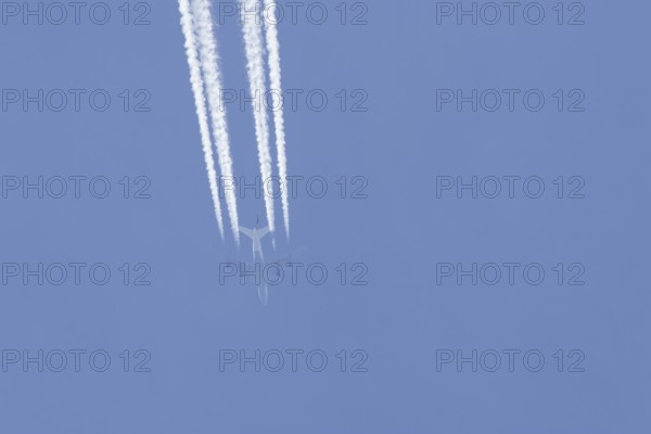 Boeing 747 jumbo jet passenger aircraft of Lufthansa airlines flying in a blue sky with contrails