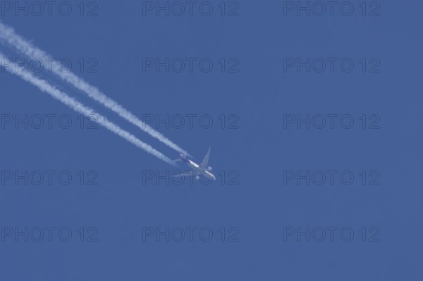 Boeing 777 jet cargo aircraft of FedEx Express airlines flying in a blue sky with contrails or