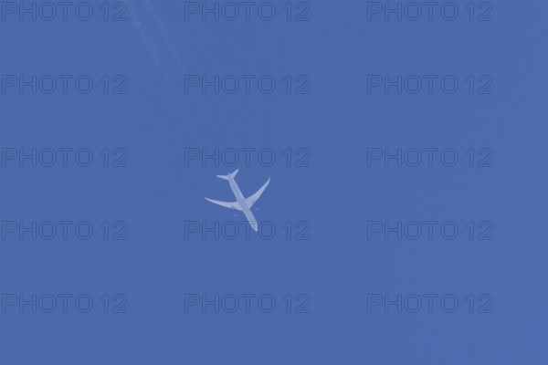 Boeing jet passenger aircraft flying in a blue sky with contrails or vapour trails behind, England,