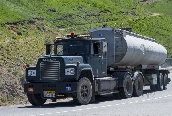 A green truck with a tank trailer is driving on a mountain road, Mack truck with Iranian license