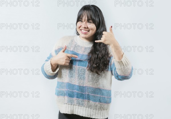 Cheerful asian woman gesturing CALL ME in sign language isolated. Beautiful girl making gesture