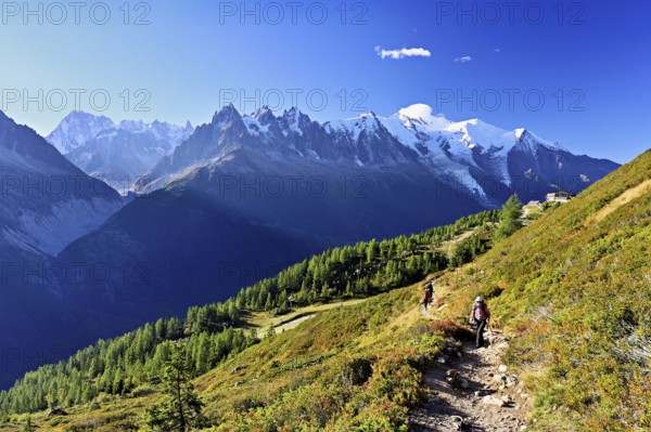 Female hiker on a hiking trail with the La Flégère cable car mountain station and the snow-covered