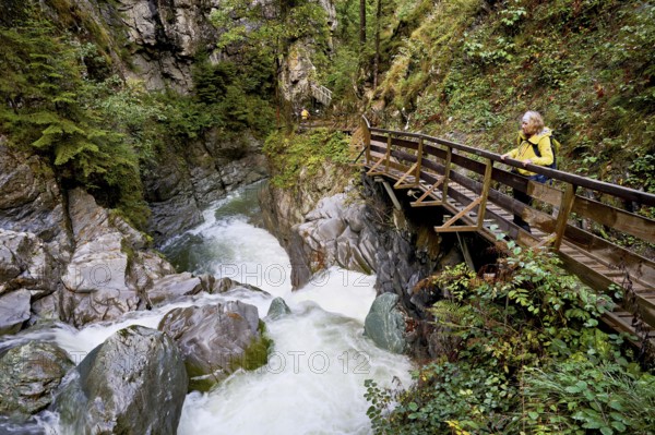 Female hiker standing on wooden walkway, Diosaz mountain river in the gorge, Gorges de la Diosaz,