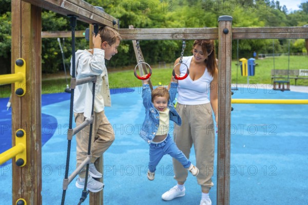 Two brothers and their mother are having fun on a playground jungle gym, with one child climbing a