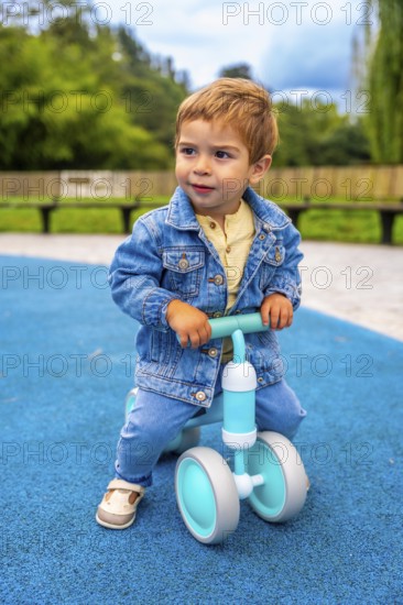 Cheerful toddler riding a balance bike in a vibrant playground, developing motor skills and