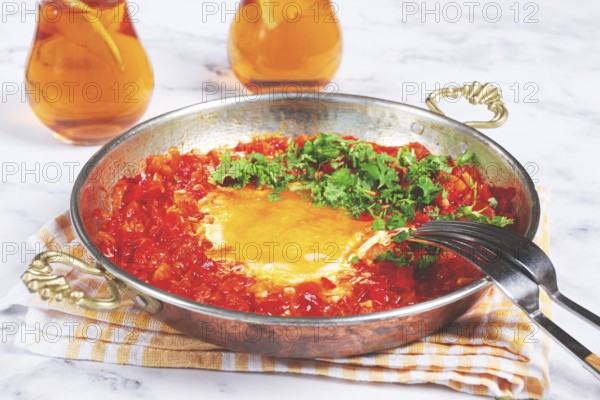 Traditional Turkish dish, scrambled eggs with tomatoes, Menemen, with herbs, in a frying pan,
