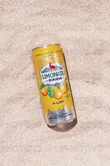 Carbonated lemonade with pear flavor, in an iron jar, Georgian drink, Borjomi, on a sandy beach,