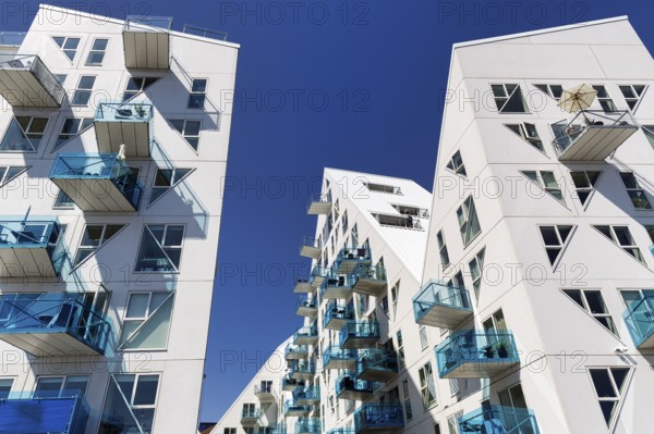 Distinctive white residential complex, turquoise balconies against blue sky, pyramid-shaped