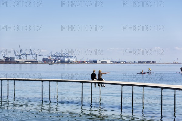 Two passers-by on circular bridge construction, wooden jetty, Infinite Bridge on Varna Beach,