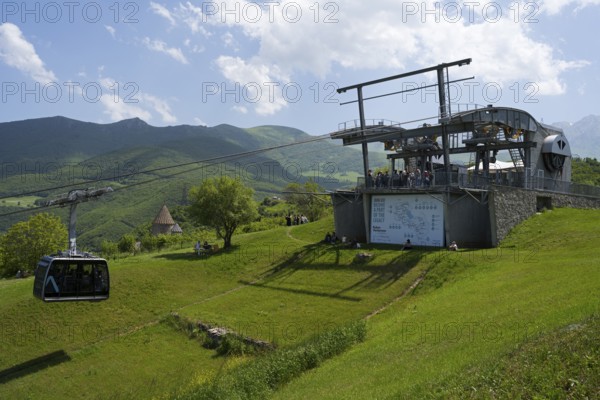 Cable car complex on green field against a background of mountains and cloudy sky, Tatev cable car,