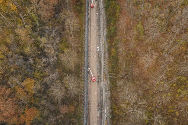 Aerial view of construction work along a slope in an autumn forest area, construction of the