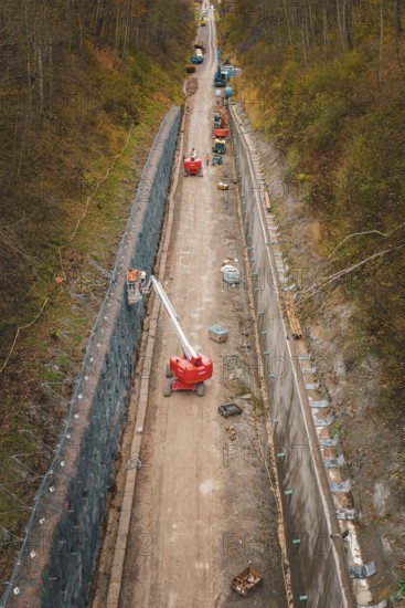Construction work on a path in a wooded area with machines and a lift, construction of the Hermann