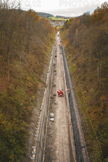View of a construction site in a wooded autumn landscape with construction equipment and excavation