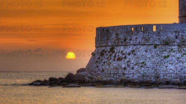 Agios Nikolaos fortress, sunrise behind an old castle wall with gentle sea waves, UNESCO World