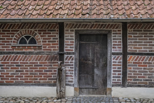 Wooden door in a traditional brick frame wall with roof tiles, Münsterland, North Rhine-Westphalia,