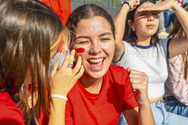 Young woman with red face paint cheering joyfully and raising her fist, celebrating team victory