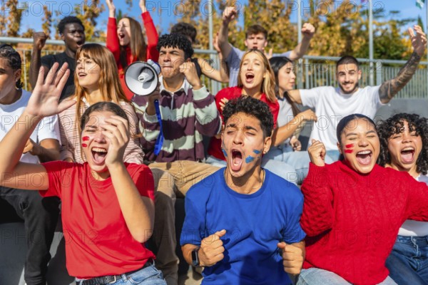 Enthusiastic young fans of diverse ethnicities and genders celebrating and cheering loudly,