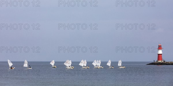 Sailing course with Optimist class sailboats, a sailing dinghy and the pier fire in Warnemünde,