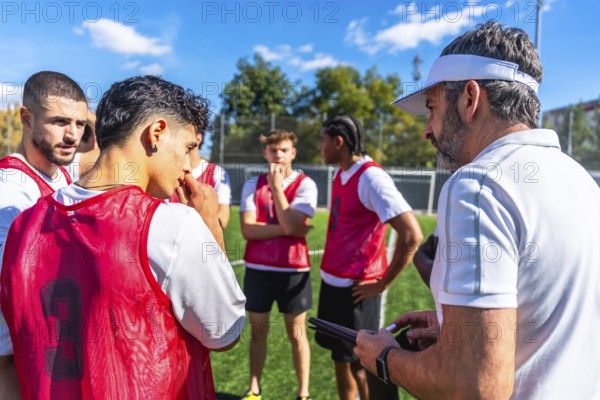Soccer coach providing instructions and discussing game strategy with a group of young male team