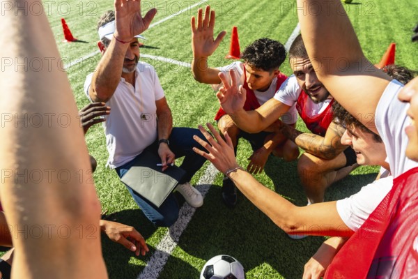 Soccer coach giving instructions and motivating his diverse team during a huddle on a green turf