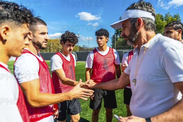 Soccer coach motivating and encouraging young male players with a handshake on a training field