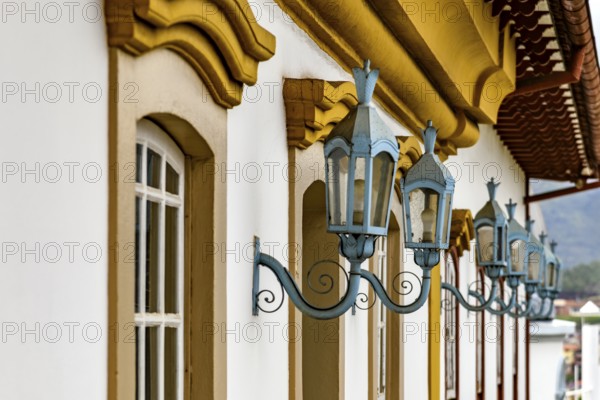 Antique metal lanterns decorating the facade of a historic colonial-style house in the city of Ouro