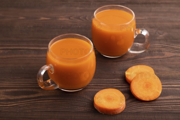 Two glasses with carrot juice, on wooden background. Diet, healthy eating concept. side view, close