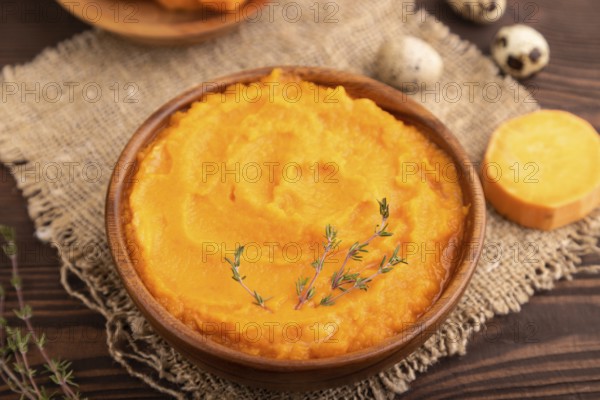 Sweet potato porridge in wooden bowl on wooden background and linen textile. Diet, healthy eating