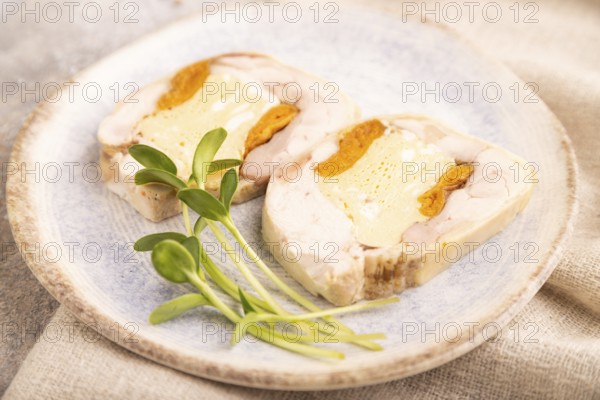 Chicken, egg and dried apricot meatloaf, microgreen on brown concrete background and linen textile.