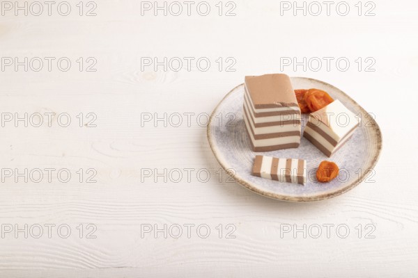 Cocoa and milk jelly with dried apricots on white wooden background, side view, copy space,