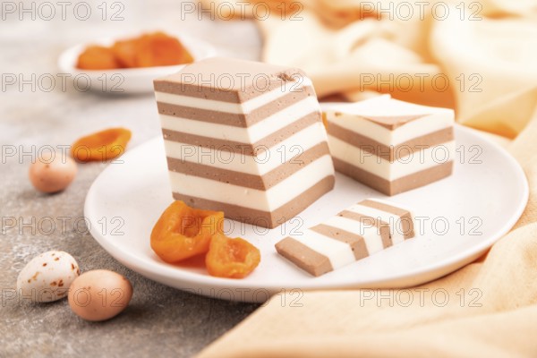 Cocoa and milk jelly with dried apricots on brown concrete background and orange textile, side