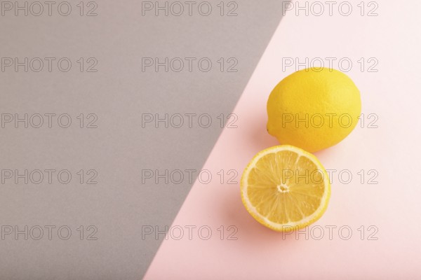 Yellow Lemon Cut in half on gray and pink pastel paper background. Side view, copy space. healthy