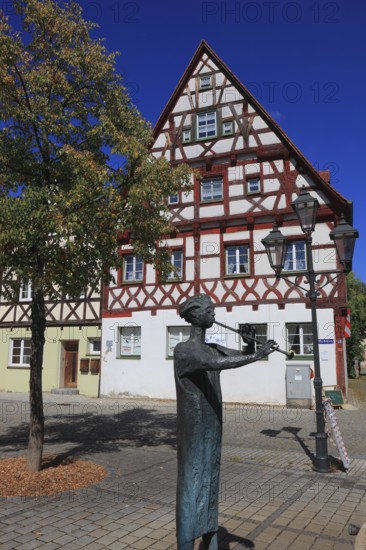 Half-timbered houses and fountain figure flute player, on Rathausplatz, city of Heideck in the