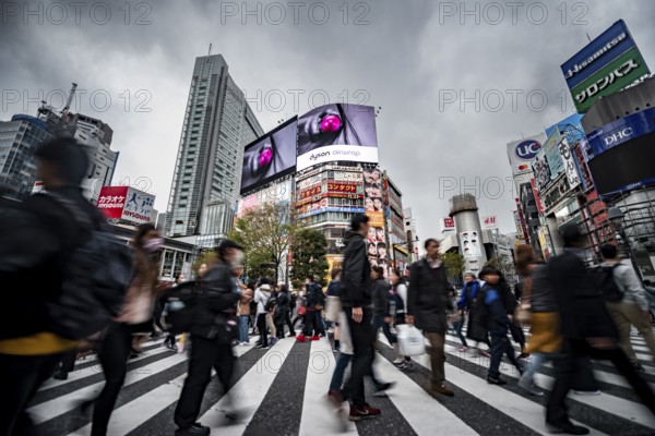 Crowd crossing zebra crossing on a large intersection, motion blur, back modern houses with