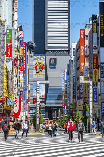 Bustling street scene in Japan with modern buildings and colorful billboards, figure of Godzilla