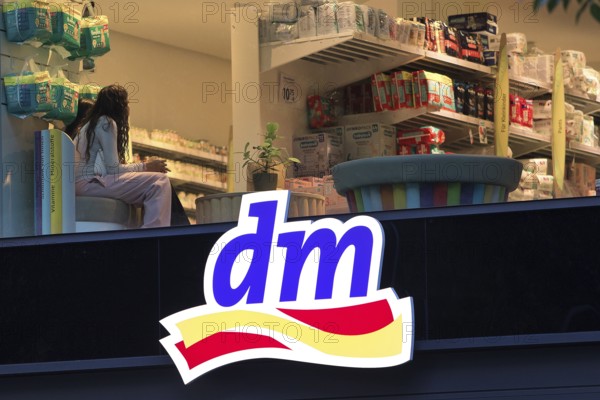 Illuminated logo of a dm drugstore branch at dusk with an insight into the shop, Tauentzienstraße,