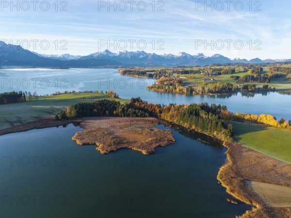 Clear lake with surrounding colorful autumn forests and the Alps in the background, Illasbergsee,