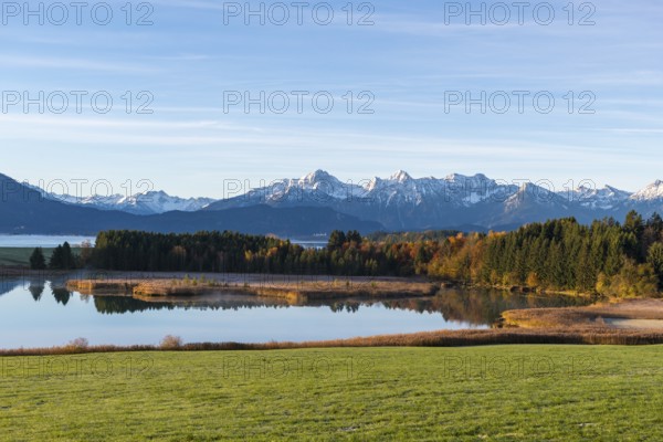 View of a lake surrounded by forests and snow-covered mountains in an autumnal atmosphere,