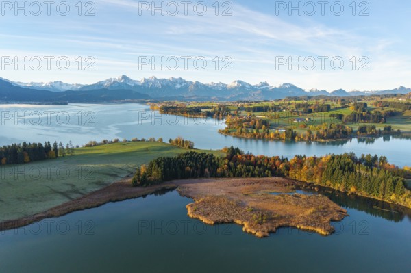 Landscape with clear lake surrounded by autumn forests and alpine scenery on the horizon,