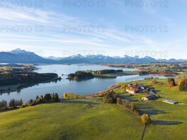 Extensive landscape with mountains in the background, a lake and green meadows in the foreground,