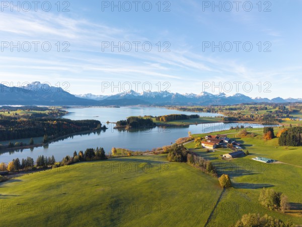 Green meadows and a farm on the shore of a lake with mountains in the background, Illasbergsee,