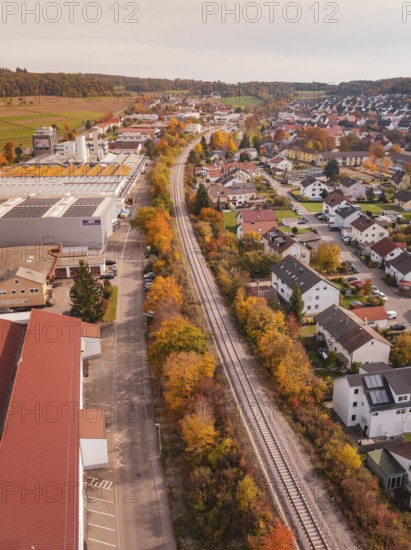 A Hermann Hesse Railway line runs through a town with autumn leaves, surrounded by residential