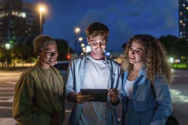Three diverse friends, two women and one man, standing on a city street at night, smiling and